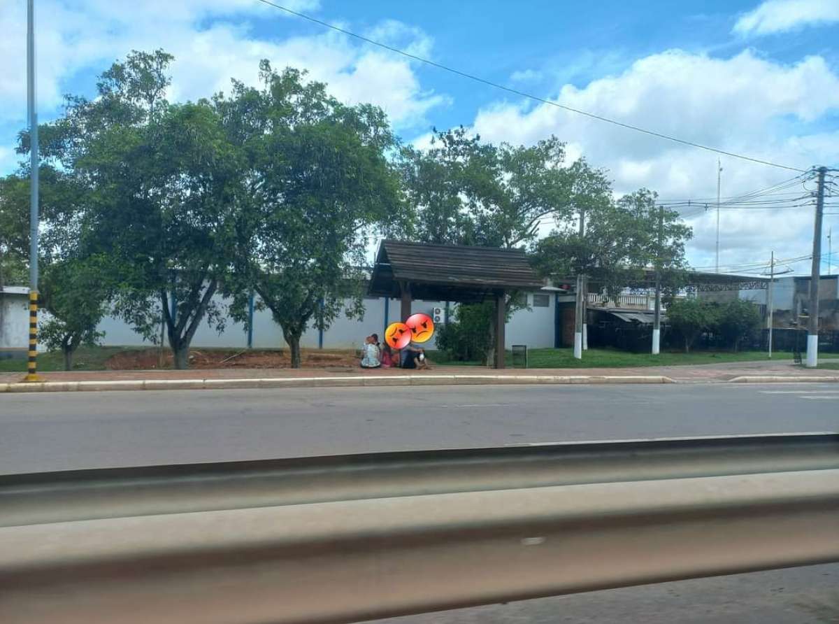 Passageiros esperam ônibus sentado no chão por falta de banco em parada 