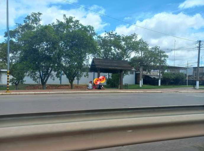 Passageiros esperam ônibus sentado no chão por falta de banco em parada 